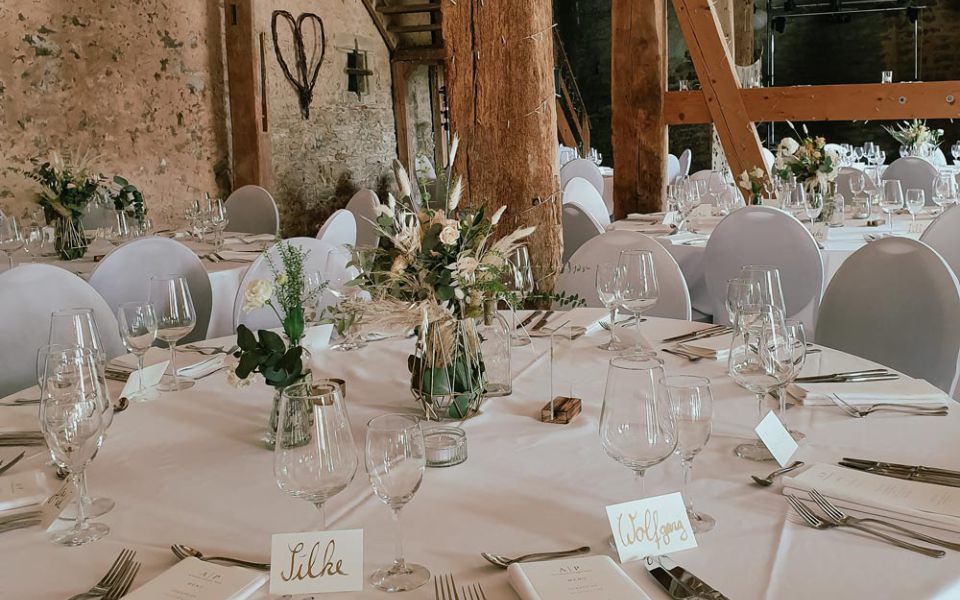 Runder, gedeckter Tisch mit Namensschildern und Blumen.