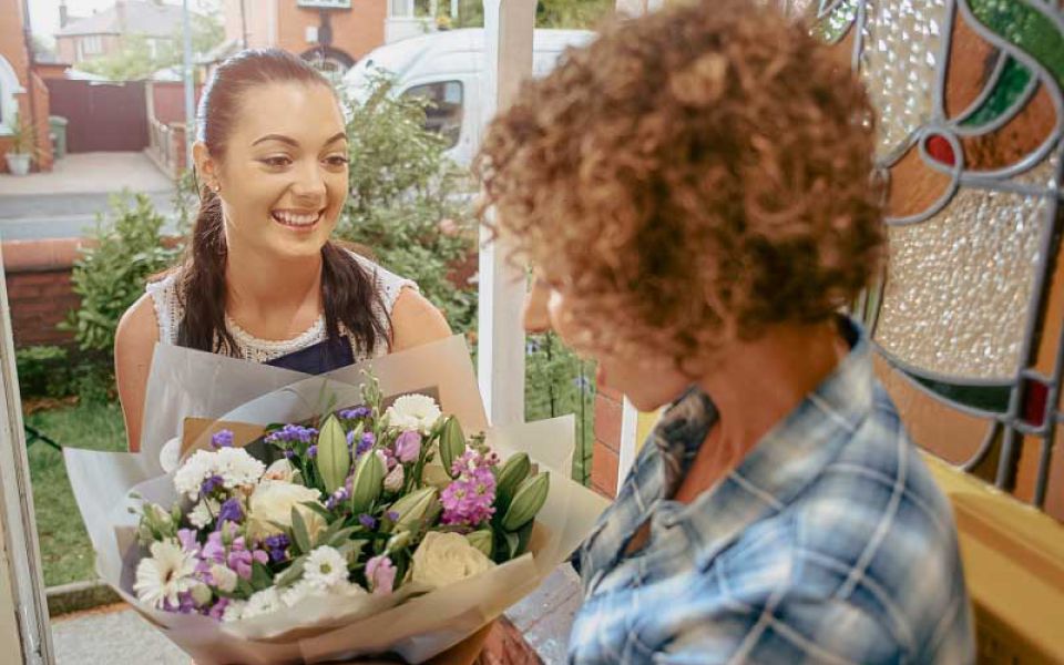 Runder, gedeckter Tisch mit Namensschildern und Blumen.